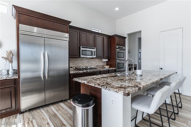 kitchen with light hardwood / wood-style floors, stainless steel appliances, a center island with sink, and sink