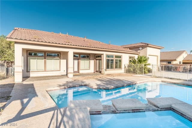 rear view of property featuring a swimming pool with hot tub and a patio area