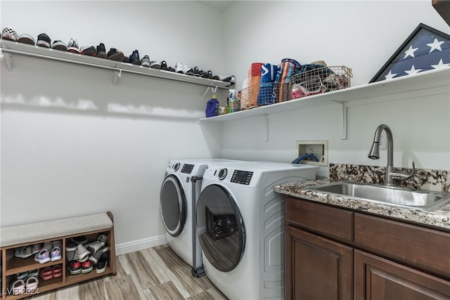 laundry room featuring sink, independent washer and dryer, light hardwood / wood-style floors, and cabinets