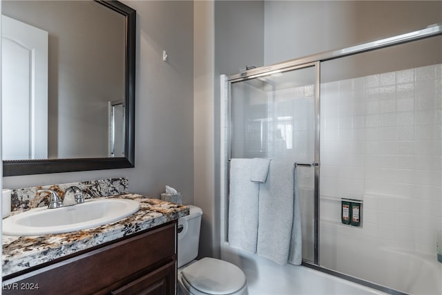 full bathroom featuring toilet, vanity, and shower / bath combination with glass door