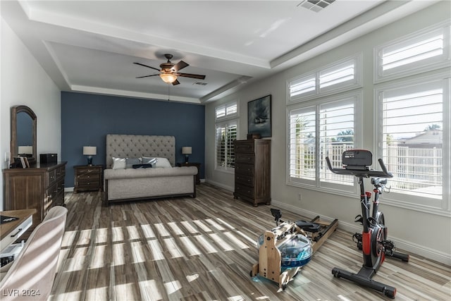 bedroom with hardwood / wood-style floors, ceiling fan, and a raised ceiling