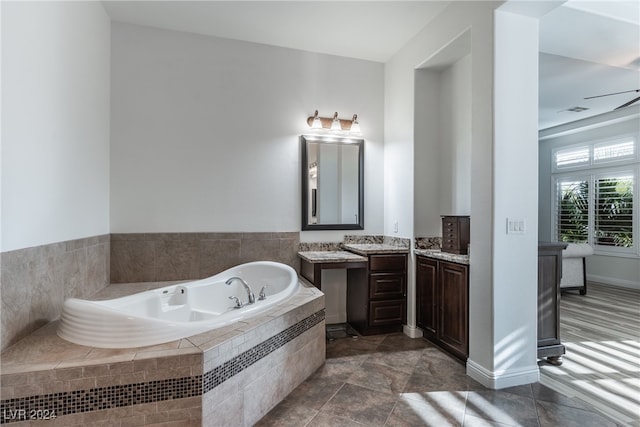 bathroom featuring vanity, tile patterned flooring, tiled tub, and ceiling fan