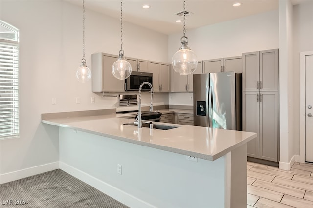 kitchen with kitchen peninsula, gray cabinetry, pendant lighting, and stainless steel appliances