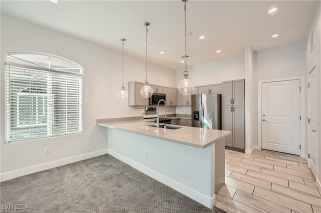 kitchen with gray cabinetry, stainless steel appliances, kitchen peninsula, light colored carpet, and decorative light fixtures