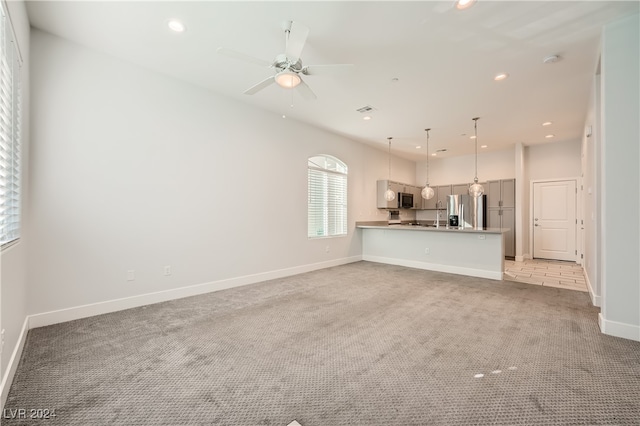 unfurnished living room featuring ceiling fan and light colored carpet