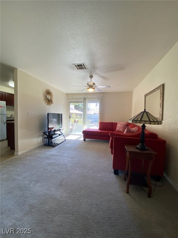 living room with a textured ceiling, ceiling fan, and carpet