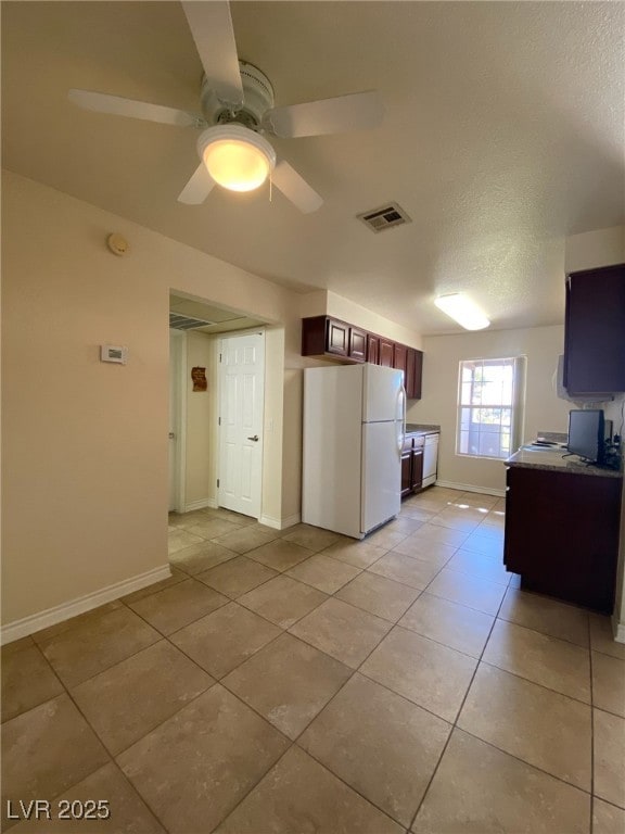 kitchen with light tile patterned floors, ceiling fan, white refrigerator, and a textured ceiling