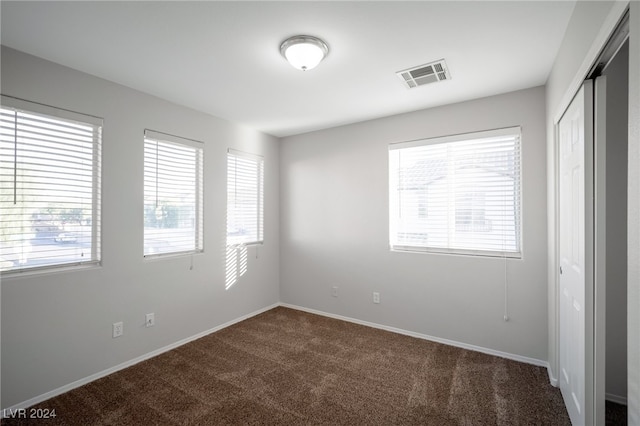 spare room with dark carpet and a wealth of natural light