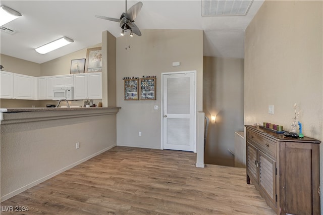 kitchen with white cabinetry, ceiling fan, vaulted ceiling, and light wood-type flooring