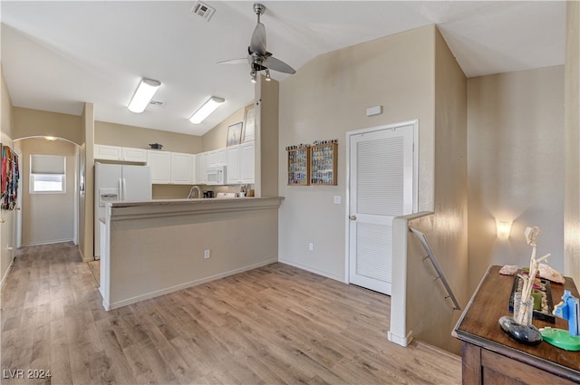 kitchen featuring white appliances, kitchen peninsula, light hardwood / wood-style floors, vaulted ceiling, and white cabinets