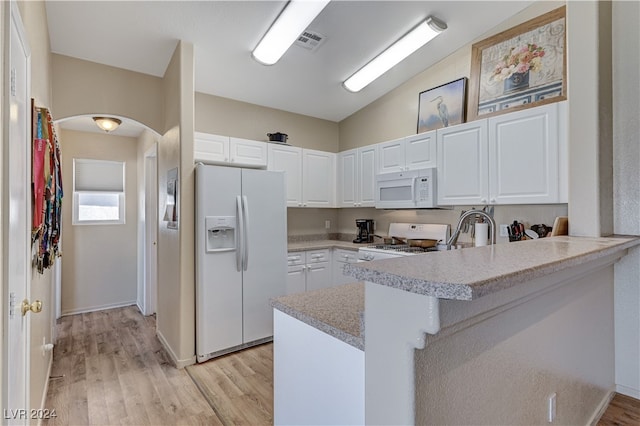 kitchen featuring white appliances, white cabinetry, lofted ceiling, and kitchen peninsula