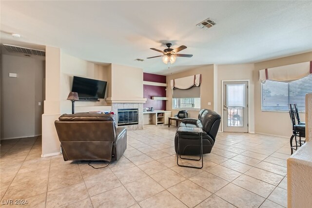 living room with a tiled fireplace, light tile patterned floors, and ceiling fan