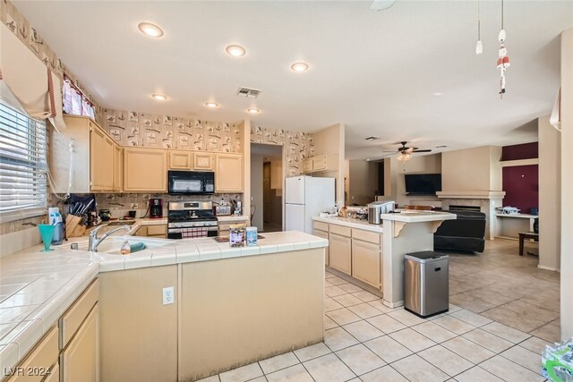 kitchen with a kitchen island, tile counters, white refrigerator, stainless steel stove, and light tile patterned floors