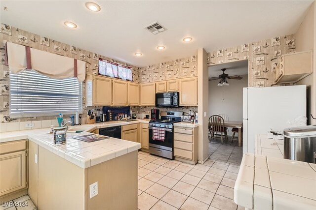 kitchen featuring tile counters, sink, black appliances, light tile patterned floors, and ceiling fan