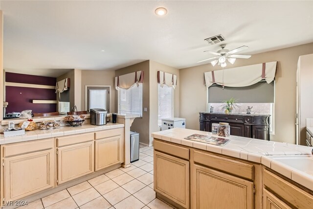 kitchen featuring tile countertops, light brown cabinets, light tile patterned floors, and ceiling fan