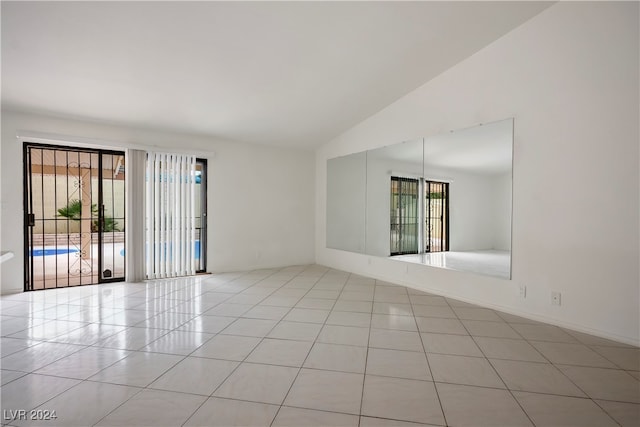 empty room featuring vaulted ceiling and light tile patterned floors