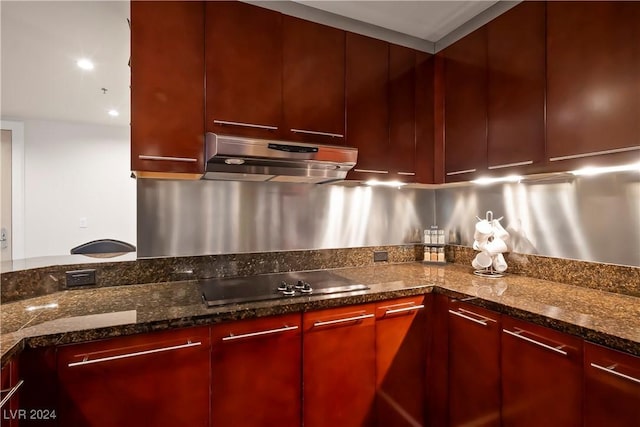 kitchen with modern cabinets, under cabinet range hood, reddish brown cabinets, and black electric cooktop