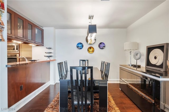 dining area featuring dark wood-type flooring and baseboards