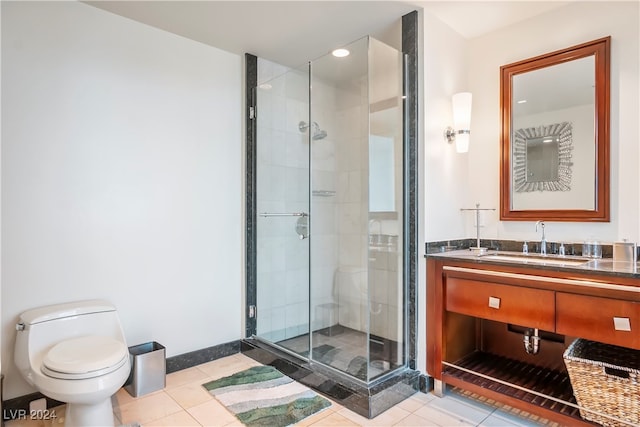 bathroom with toilet, a shower with shower door, vanity, and tile patterned flooring