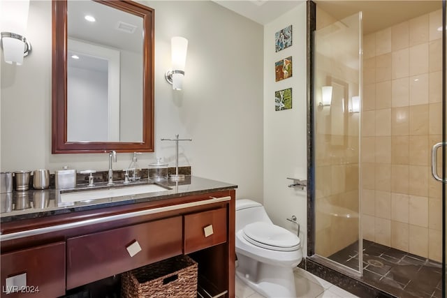 bathroom featuring toilet, a shower with shower door, vanity, and tile patterned floors