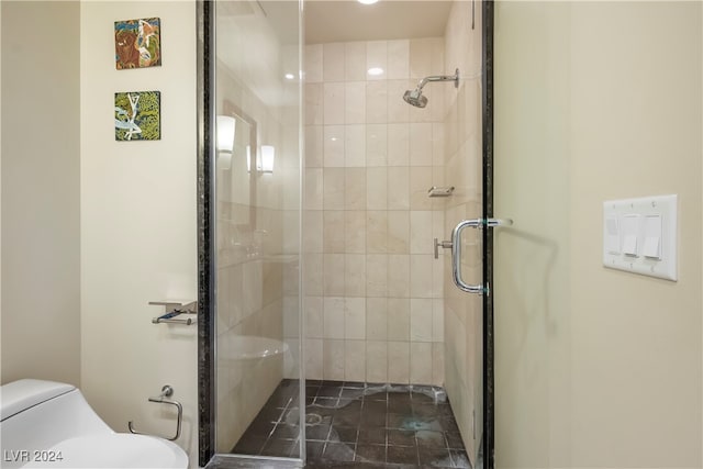 bathroom featuring a shower with shower door and toilet