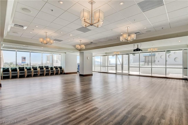 workout area featuring an inviting chandelier, a paneled ceiling, plenty of natural light, and wood finished floors