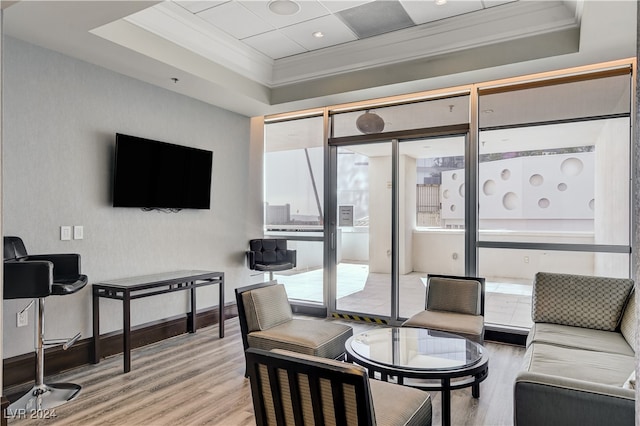 living room with crown molding, a tray ceiling, and light wood-type flooring