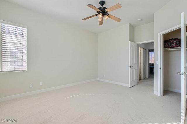 unfurnished bedroom with a closet, light colored carpet, and ceiling fan