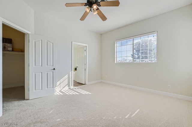 unfurnished bedroom featuring a spacious closet, ceiling fan, a closet, and light colored carpet