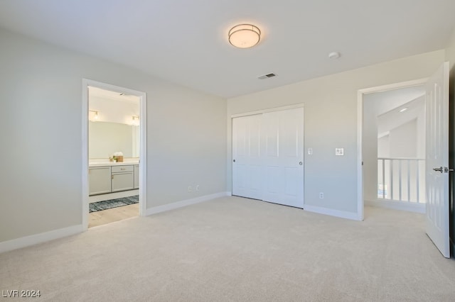 unfurnished bedroom featuring a closet, light colored carpet, and connected bathroom