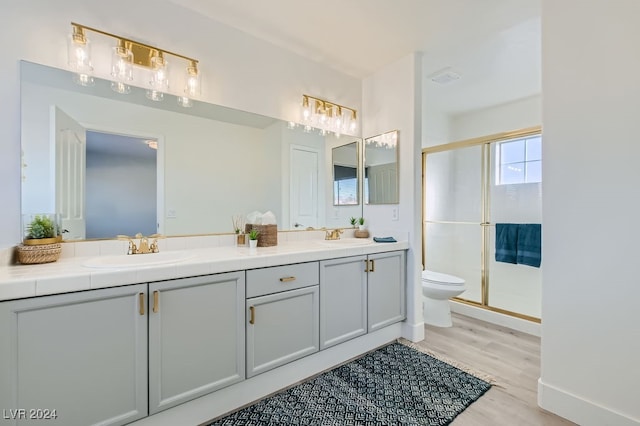 bathroom with toilet, a shower with shower door, vanity, and wood-type flooring