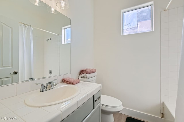 full bathroom featuring vanity, shower / bath combo, toilet, and a healthy amount of sunlight