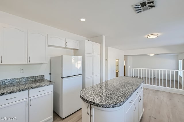 kitchen with white cabinets, white fridge, a center island, and light wood-type flooring