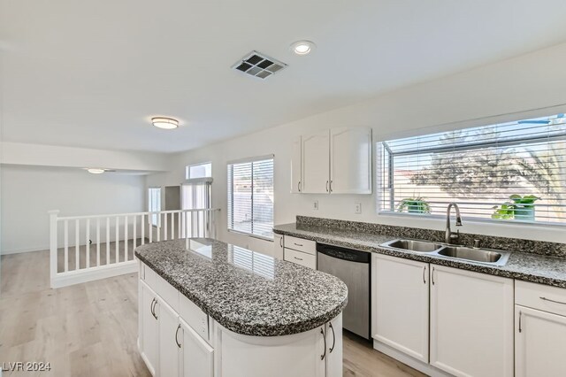 kitchen with light hardwood / wood-style floors, sink, stainless steel dishwasher, and a kitchen island