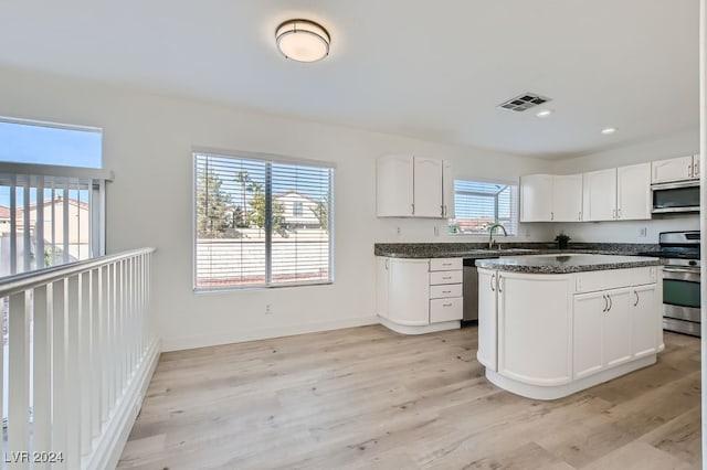 kitchen with a center island, stainless steel appliances, a wealth of natural light, and light hardwood / wood-style floors