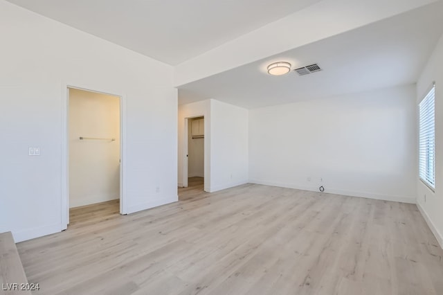 unfurnished bedroom with a closet, light hardwood / wood-style floors, and a walk in closet