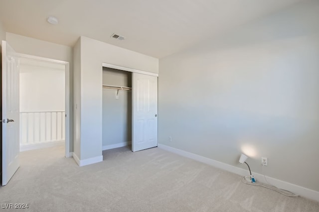 unfurnished bedroom featuring a closet and light colored carpet