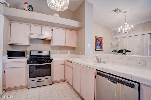 kitchen featuring sink, appliances with stainless steel finishes, tile counters, and an inviting chandelier