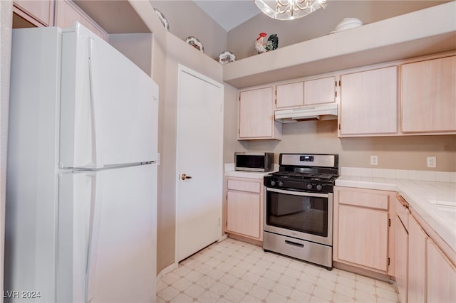 kitchen with tile countertops, appliances with stainless steel finishes, lofted ceiling, and a chandelier