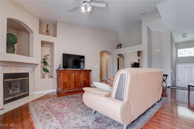 living room with a high ceiling, light hardwood / wood-style flooring, a fireplace, and ceiling fan