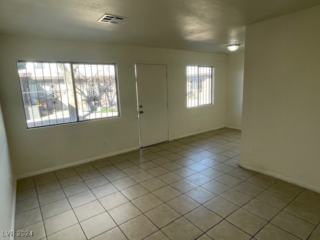 unfurnished room with light tile patterned flooring and a wealth of natural light