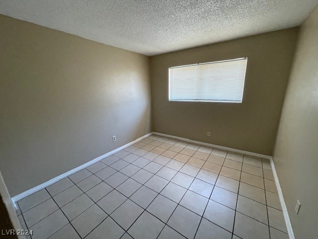 tiled empty room with a textured ceiling