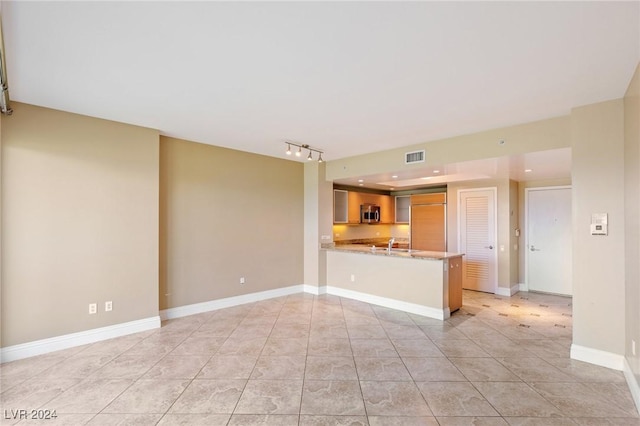 unfurnished living room featuring light tile patterned floors and sink