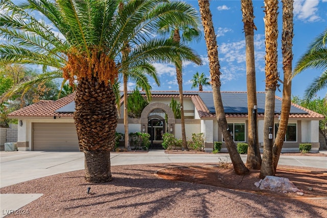 mediterranean / spanish-style home with a garage and solar panels