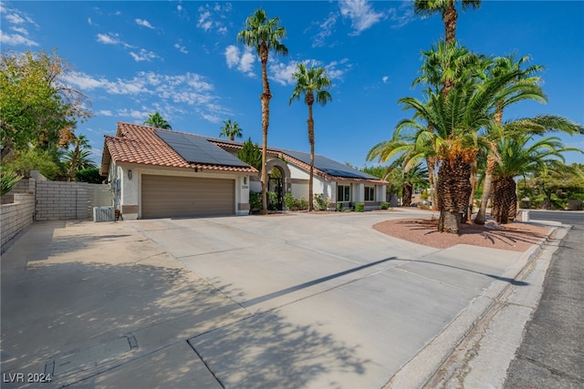 view of front of home with central AC unit, a garage, and solar panels