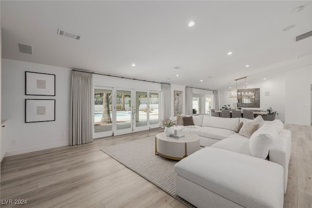 living room with a chandelier, french doors, and light wood-type flooring