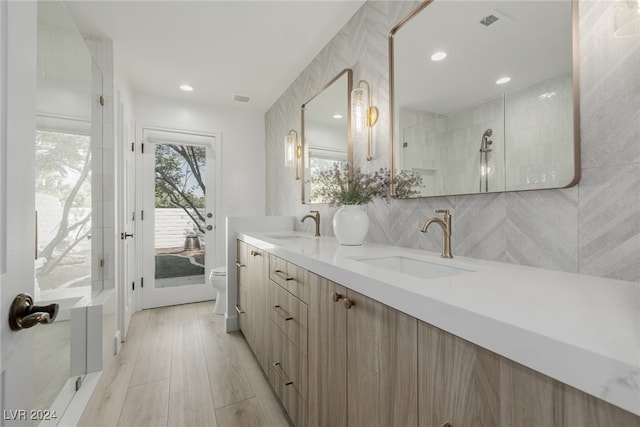 bathroom featuring tile walls, vanity, a tile shower, and toilet