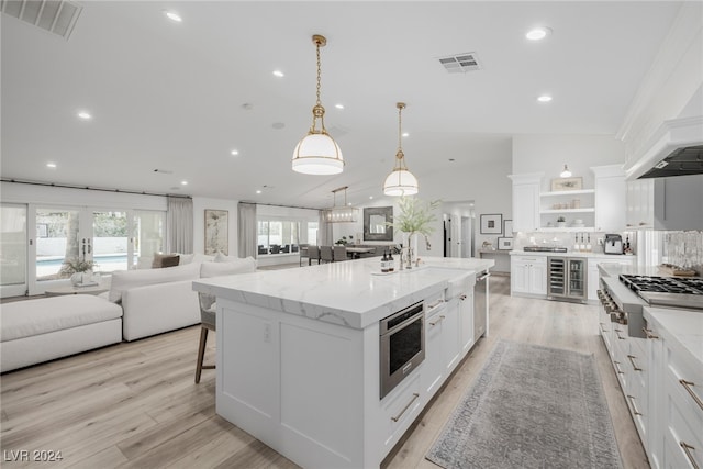 kitchen with sink, light wood-type flooring, a large island, white cabinetry, and pendant lighting