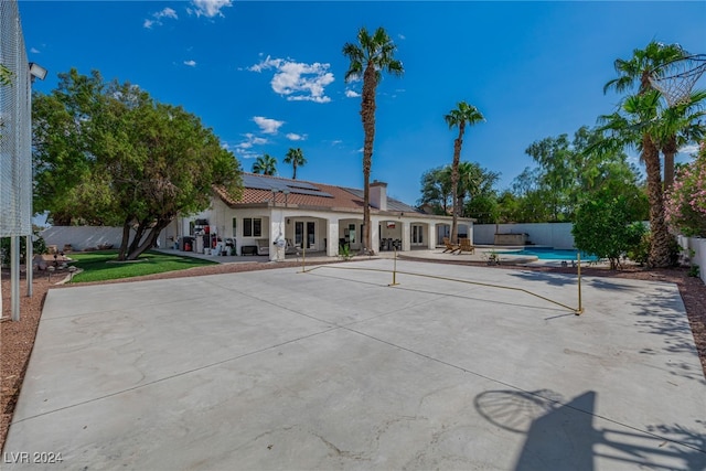 back of house with solar panels, a patio, and a fenced in pool