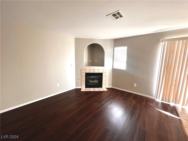 unfurnished living room with dark hardwood / wood-style flooring and a tile fireplace